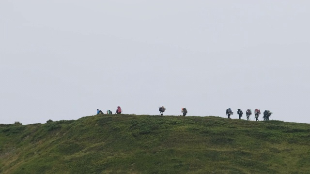 一群背着徒步背包的游客攀登山脉。远处的观点视频素材