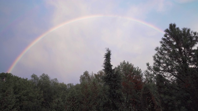 森林上空双彩虹，雨后蓝天。彩色的云。视频素材