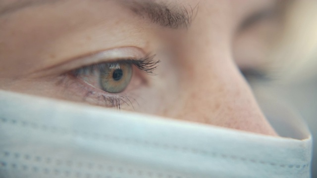 特写肖像的现代休闲年轻的一个女人戴着防护医疗面罩和看。安全概念和睁开眼睛的人在社会距离隔离。微距慢动作拍摄4k视频素材