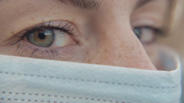 特写肖像的现代休闲年轻的一个女人戴着防护医疗面罩和看。安全概念和睁开眼睛的人在社会距离隔离。微距慢动作拍摄4k视频素材