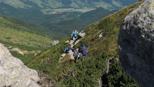 一群背着背包的游客和孩子们沿着山上的石头小径下山视频素材