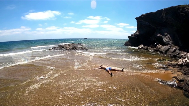 绿松石般的海滩，田园般的海景。西班牙海滩的旅游目的地。一个人躺在海边的浅水上视频素材