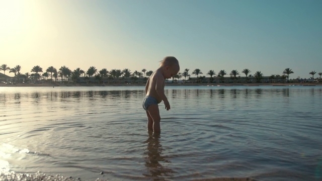 可爱活泼的幼童在夏天的海岸线掉进海水里。视频素材