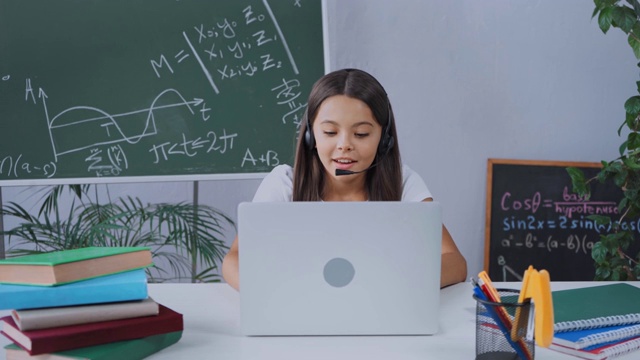 女学生戴着耳机在家里在线学习时进行视频聊天视频素材