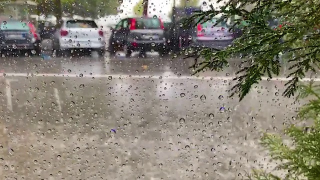 城市街道上模糊的物体和雨滴落在窗户玻璃上。圆点图案的圆形雨滴看起来像珠子视频素材