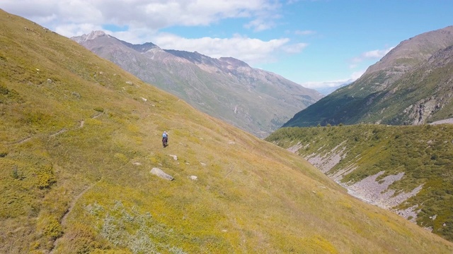 在山上骑马的人的顶视图。夹。在蓝天的背景下，黄色的山坡上骑着马的山景。骑手骑马穿过山口视频素材