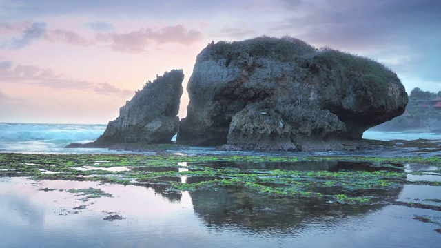 岩石海滩海浪白色泡沫水溅击中悬崖岩石在黄昏视频素材