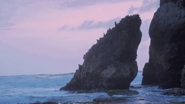 岩石海滩海浪水花击中悬崖岩石在傍晚黄昏视频素材