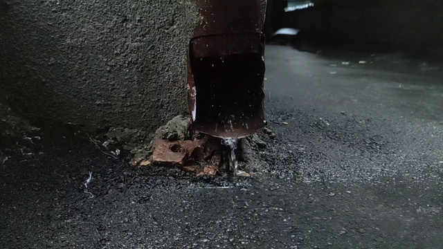 秋雨在城中。雨水从排水管流出，雨滴落在潮湿的沥青上视频素材