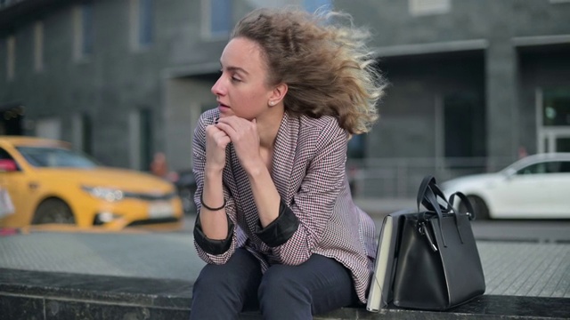 这位沉思的年轻女子坐在街上思考着什么视频素材