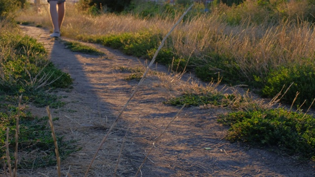 一个男人在阳光明媚的天气下走在乡村道路上的夏天鞋子的腿的特写。积极的生活方式的概念。视频素材