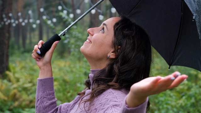 快乐的女人带着伞检查下雨视频素材