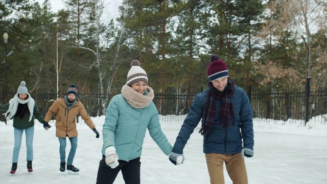 男人和女人在冰天雪地的公园里的溜冰场玩得很开心视频素材