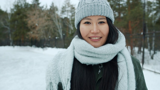 肖像美丽的亚洲女士穿着冬装站在户外公园微笑视频素材