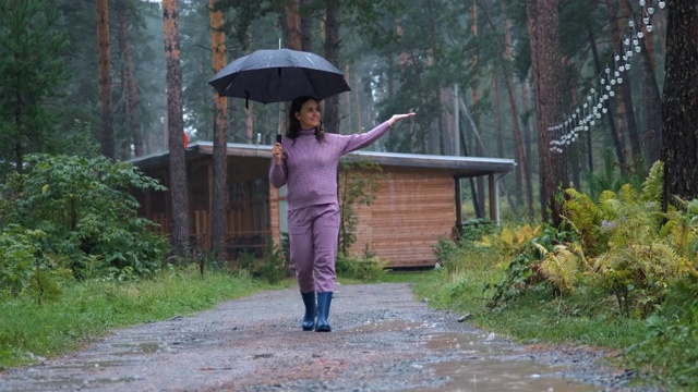 带着伞的女人，在雨中漫步视频素材