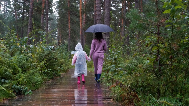 和妈妈一起享受雨中漫步的小女孩视频素材