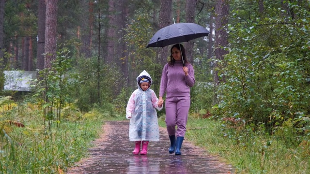 母亲和女儿走在秋天的雨天视频素材