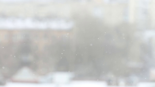 白色的雪花飘落在城市景观模糊的背景。梦幻般的寒冷冬天。圣诞节和新年的概念视频素材