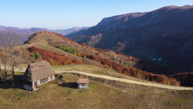 罗马尼亚特兰西瓦尼亚的空中秋日乡村山景，有木屋、茅草屋顶和土路视频素材