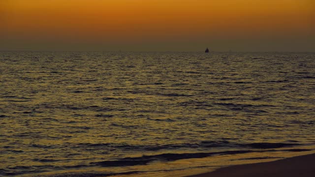 海浪在夕阳的背景，美丽的自然海景，红色的太阳和金色的天空和云的背景，风在海上反射光是美丽的，黄昏在海滩上看自然，度假的人旅游视频素材