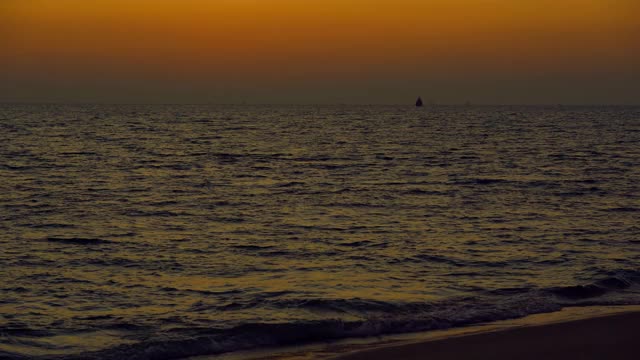 海浪在夕阳的背景，美丽的自然海景，红色的太阳和金色的天空和云的背景，风在海上反射光是美丽的，黄昏在海滩上看自然，度假的人旅游视频素材