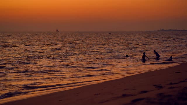 海浪在夕阳的背景，美丽的自然海景，红色的太阳和金色的天空和云的背景，风在海上反射光是美丽的，黄昏在海滩上看自然，度假的人旅游视频素材