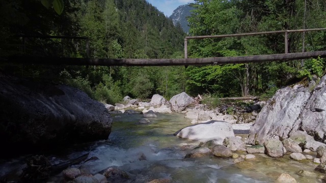 小高山河流，飞过岩石，绿色河岸与落叶树之间，阳光反射视频素材