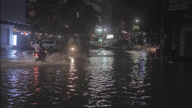 晚上下雨时，摩托车穿过被水浸透的街道视频素材