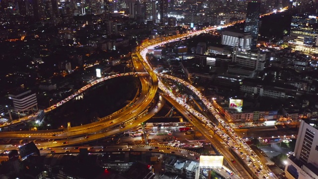 在高速公路路口行驶的汽车鸟瞰图。桥梁、街道、道路在建筑网络中的连接概念。前视图。曼谷夜市，泰国。视频素材