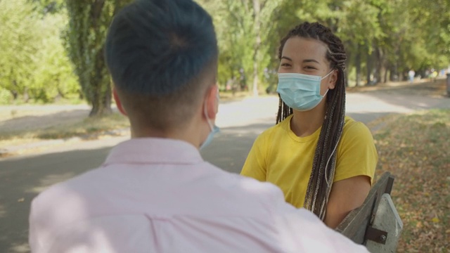 年轻的亚洲女性在防护面具交谈朋友在户外，保健视频素材