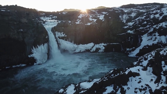 Aldeyjarfoss。水流冲下冰封的峡谷，升起的太阳照亮了这片景色。视频素材