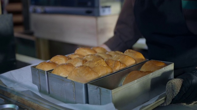 在烹饪中，女厨师面包师戴着手套，为咖啡馆、餐馆和小企业的游客们准备了新鲜的热面点，香喷喷的面包视频素材