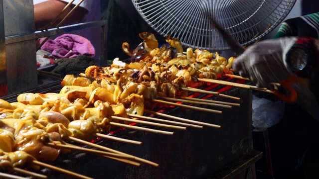 在泰国街头食物的木炭炉上烤鱿鱼在晚上视频素材