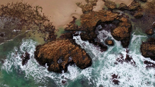 海浪撞击海滩附近的岩石的鸟瞰图视频素材