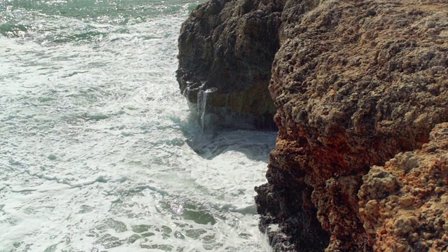 在阳光明媚的日子里，海浪拍打着岩石海岸，这是慢动作视频视频素材