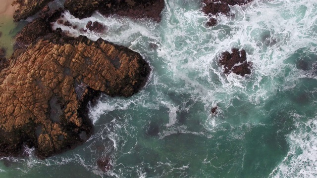 海浪撞击海滩附近的岩石的鸟瞰图视频素材