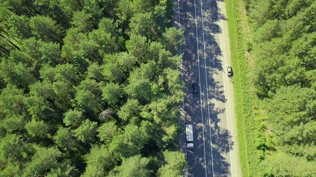 空中飞行:飞过森林里的汽车和卡车的公路。此外，汽车停在路边。视频素材