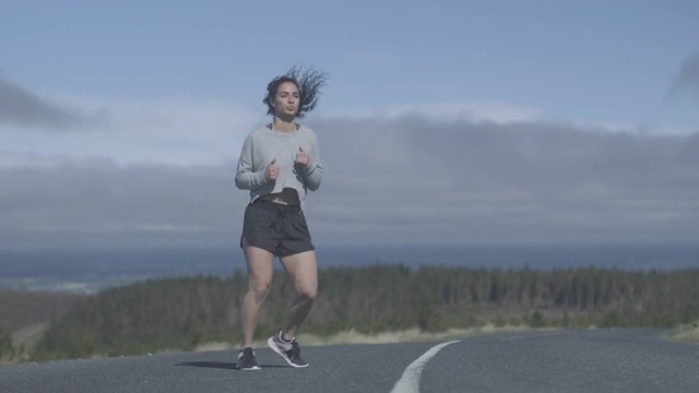 年轻女子在外面的山路上跑步视频素材