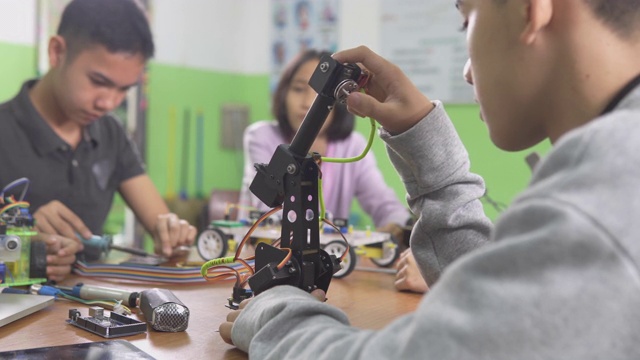 教育主题:聪明的学校男孩建立一个小机器人手臂和使用笔记本电脑编程软件的机器人工程类作为学校科学项目。科学与人的观念。视频素材