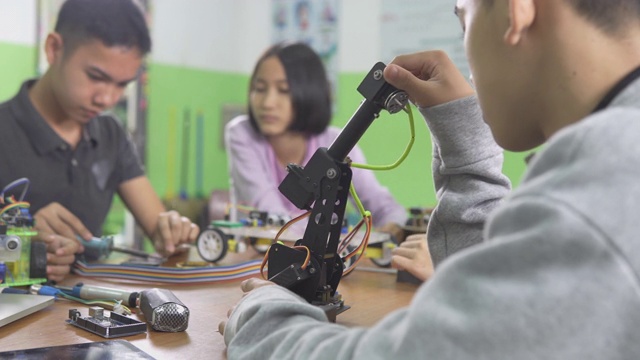 教育主题:聪明的学校男孩建立一个小机器人手臂和使用笔记本电脑编程软件的机器人工程类作为学校科学项目。科学与人的观念。视频素材