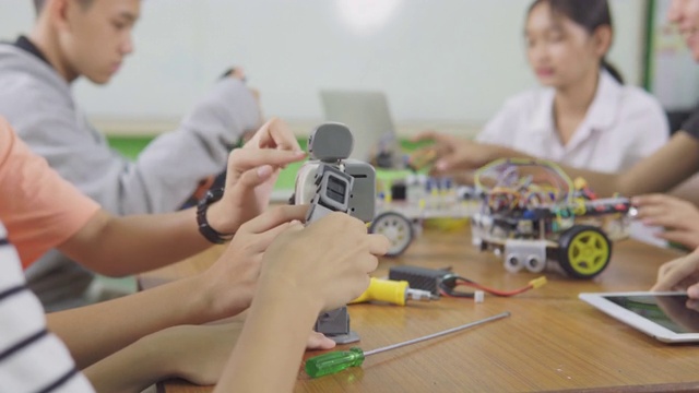 教育主题:聪明的学校男孩建立一个小机器人手臂和使用笔记本电脑编程软件的机器人工程类作为学校科学项目。科学与人的观念。视频素材