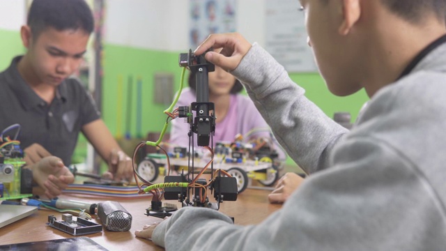 教育主题:聪明的学校男孩建立一个小机器人手臂和使用笔记本电脑编程软件的机器人工程类作为学校科学项目。科学与人的观念。视频素材