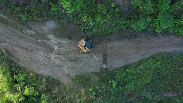 高角度的挖掘机，是在道路上工作和移除一些灌木丛视频素材