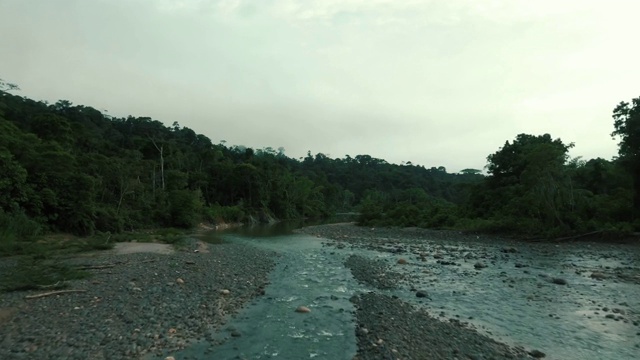 在一个阴雨霏霏的早晨，无人机沿着一条满载卵石的热带大河顺流而下视频素材