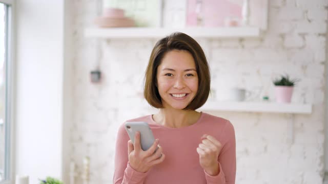 兴奋的亚洲成年女性客户庆祝得到电子商务购物优惠智能手机视频素材