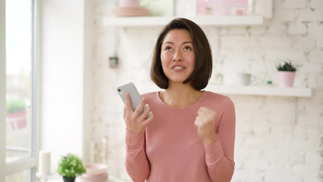 兴奋的成年亚洲女性客户庆祝在智能手机上获得电子商务购物优惠视频素材