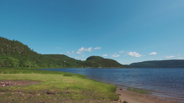 在阳光明媚的日子里，从岸边看到峡湾的风景，山上有树视频素材