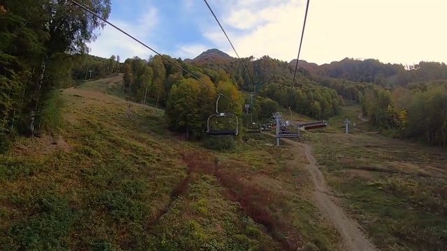 POV时间推移行走在绳索升降机在秋天的山。美丽的金色森林在阿尔卑斯山的背景下，蓝色的天空视频素材