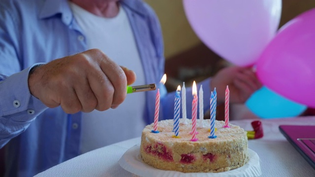 庆祝生日时，老人手里拿着球，在房间里的桌子旁坐着甜蛋糕上点上节日蜡烛，营造喜庆气氛，特写视频素材