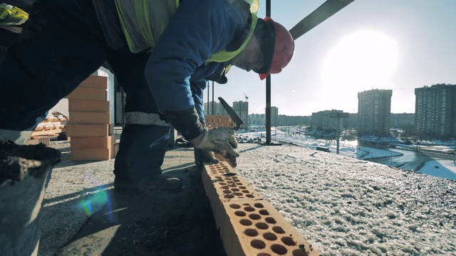 男性建筑工人把砖排成一排。建筑工地、建筑行业、建筑工人概念。视频素材